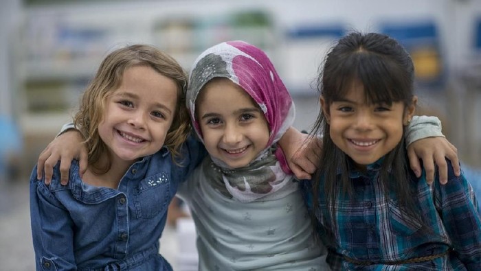 Little Muslim girl wearing a hijab is enjoying the day at school with her friends.