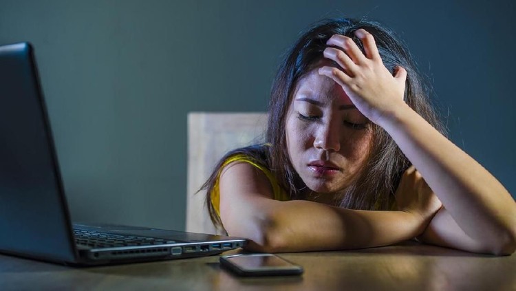 dramatic portrait scared and stressed Asian Korean teen girl or young woman with laptop computer and mobile phone suffering cyber bullying stalked and harassed with internet password hacked