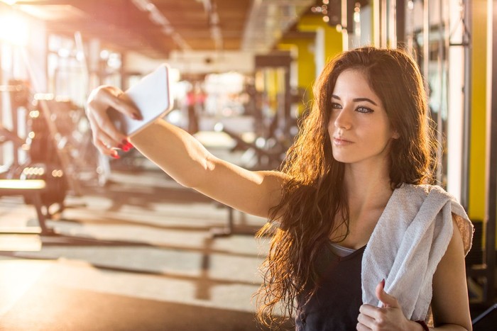 Healthy man prepare for next exercise in gym during hard cross training, while hi's friends having short rest and take a selfie. They wearing professional sport clothing .