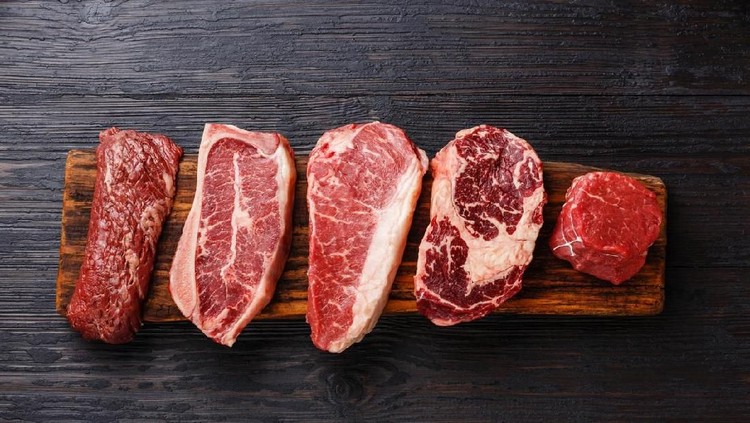 Top view of an iron grill with two fresh beef steak fillets on wooden kitchen table filled with cooking and seasoning ingredients. DSRL studio photo taken with Canon EOS 5D Mk II and Canon EF 100mm f/2.8L Macro IS USM