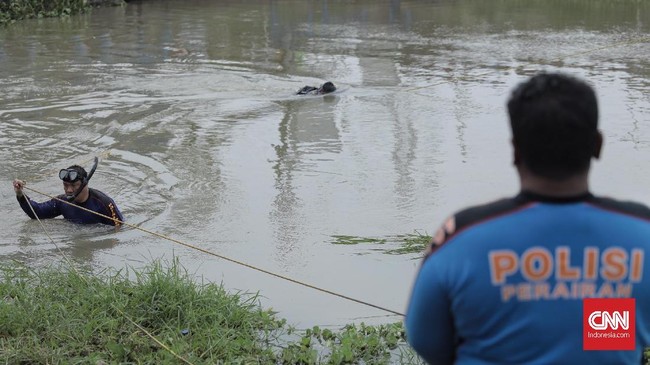 Polda Metro Jaya menerjunkan sejumlah penyelam untuk mencari barang bukti linggis di sungai Kalimalang, Jawa Barat (17/11). Linggis tersebut digunakan oleh Haris Simamora untuk membunuh satu keluarga di Bekasi (17/11). (CNN Indonesia/ Hesti Rika)
