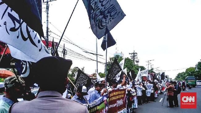 Ratusan orang mengibarkan bendera berkalimat tauhid di Mapolda Jawa Timur untuk mengawal pemeriksaan Gus Nur, terduga penghina NU dan Banser.