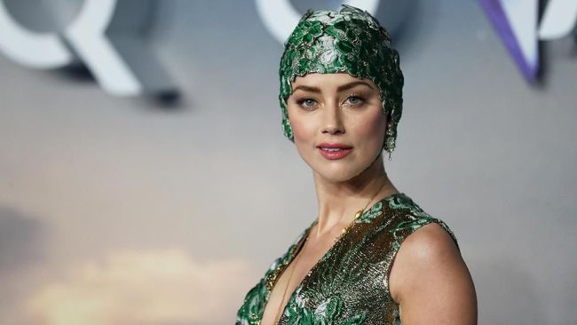 Di pemutaran perdana Aquaman di London, Amber Heard memakai gaun couture hijau-emas yang dilengkapi dengan 'topi renang' dari rumah mode Valentino. 