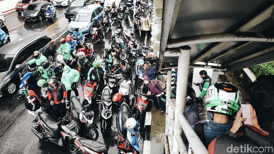 Menghindari hujan deras, sejumlah pemotor memenuhi kolong JPO di kawasan Kuningan, Jakarta untuk berteduh. Akibatnya lalu lintas menjadi tersendat.