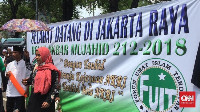 Para peserta Reuni Aksi 212 rela mengantre berfoto di depan spanduk bertuliskan 'Dengan Tauhid Kita Menuju Kejayaan NKRI, Bela Tauhid Bela NKRI'.