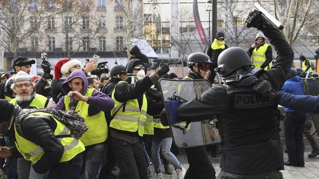Massa gerakan Rompi Kuning merangsek ke kota Paris usai Presiden Emmanuel Macron menggelar parade Hari Bastille.