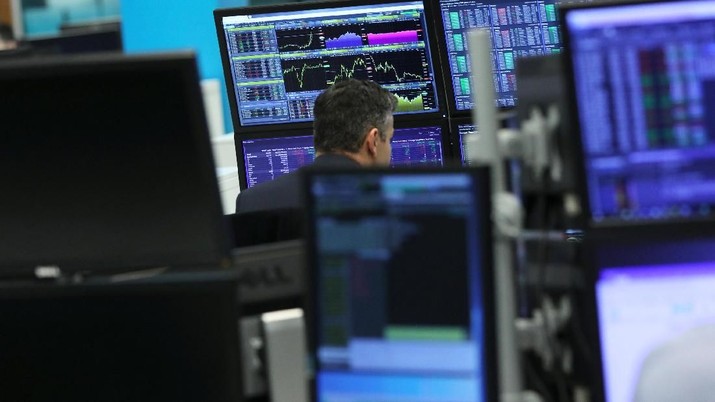 A trader works as screens show market data at CMC markets in London, Britain, December 11, 2018. REUTERS/Simon Dawson