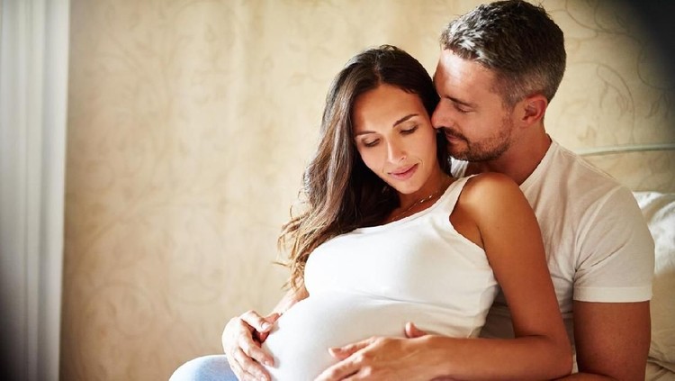 Portrait of the pregnant woman and young man together indoors