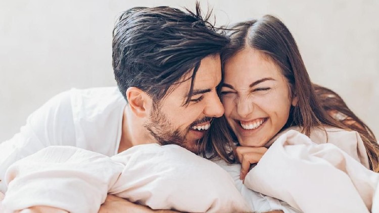Couple in bed holding hands passionately