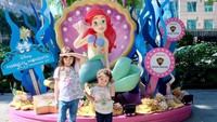 <p>Meskipun silau, tetap eksis nih si cantik Elea dan Cimbot, panggilan sayang si bungsu. Dengan gaya masing-masing pose di depan patung Little Mermaid di Disneyland Singapore. (Foto: Instagram @ussypratama)</p>