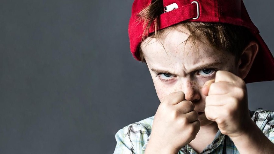 An older schoolboy bullying a younger boy isolated on white.