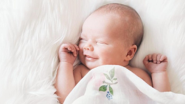 Portrait of a newborn baby girl while sleeping and smiling.