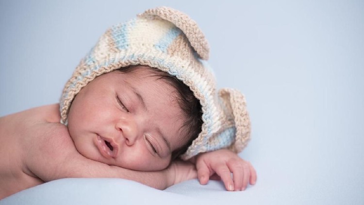 Newborn baby sleeping on white blanket and Wearing Knit Hat
