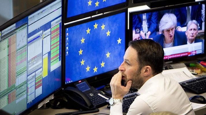 A computer screen shows news about Brexit with British Prime Minister Theresa May as a broker watches his screens at the stock market in Frankfurt, Germany, Wednesday, Jan. 16, 2019. (AP Photo/Michael Probst)