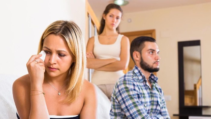 Three sad young adults arguing at domestic interior