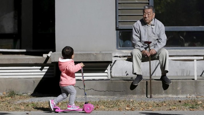 FILE PHOTO: An 80-year-old man, surnamed Li, watches as a girl plays at a residential community in Beijing, China, October 30, 2015. REUTERS/Jason Lee/File Photo