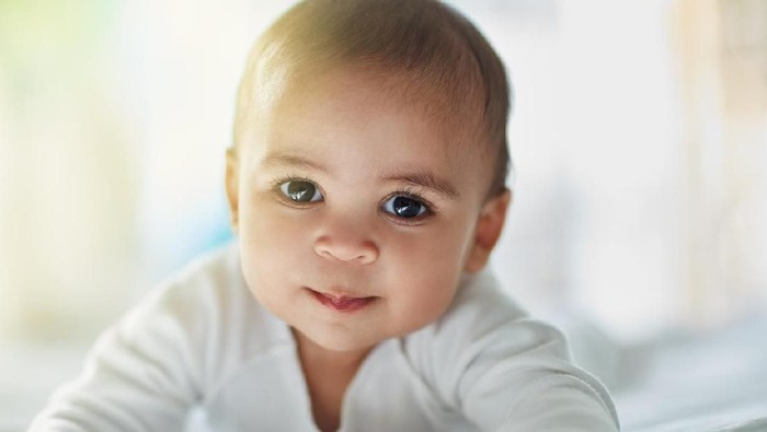 Cute little baby boy with handmade knitted cloths, playing with little teddy bear toy, smiling at camera