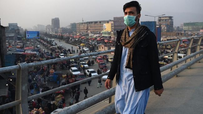 Polusi Udara di Afghanistan In this photograph taken on January 16, 2019, an Afghan resident wearing a face mask walks along an overpass amid heavy smog conditions in Afghanistan's capital Kabul. - Kabul residents have long run the gauntlet of suicide attacks and bombs. This winter, however, they face another deadly threat: air pollution. For weeks a thick layer of toxic smog has blanketed the sprawling city as cold air traps pollution caused by people burning coal, wood, car tyres and even garbage to stay warm. (Photo by WAKIL KOHSAR / AFP) / TO GO WITH: PHOTOESSAY - AFGHANISTAN-POLLUTION