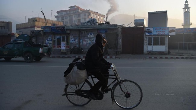 In this photograph taken on January 17, 2019, an Afghan resident rides a bicycle along a road amid heavy smog conditions in Afghanistan's capital Kabul. - Kabul residents have long run the gauntlet of suicide attacks and bombs. This winter, however, they face another deadly threat: air pollution. For weeks a thick layer of toxic smog has blanketed the sprawling city as cold air traps pollution caused by people burning coal, wood, car tyres and even garbage to stay warm. (Photo by WAKIL KOHSAR / AFP) / TO GO WITH: PHOTOESSAY - AFGHANISTAN-POLLUTION