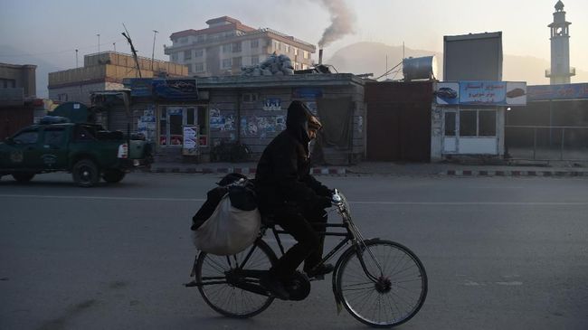Polusi Udara di Afghanistan In this photograph taken on January 17, 2019, an Afghan resident rides a bicycle along a road amid heavy smog conditions in Afghanistan's capital Kabul. - Kabul residents have long run the gauntlet of suicide attacks and bombs. This winter, however, they face another deadly threat: air pollution. For weeks a thick layer of toxic smog has blanketed the sprawling city as cold air traps pollution caused by people burning coal, wood, car tyres and even garbage to stay warm. (Photo by WAKIL KOHSAR / AFP) / TO GO WITH: PHOTOESSAY - AFGHANISTAN-POLLUTION