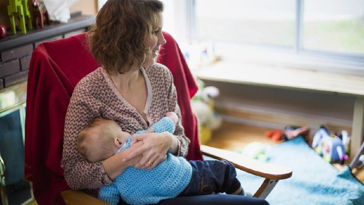 Mom breastfeeds her baby at home