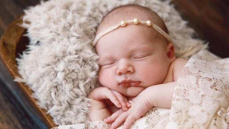 505134890 A beautiful newborn baby girl sleeps soundly in an antique wooden bowl.