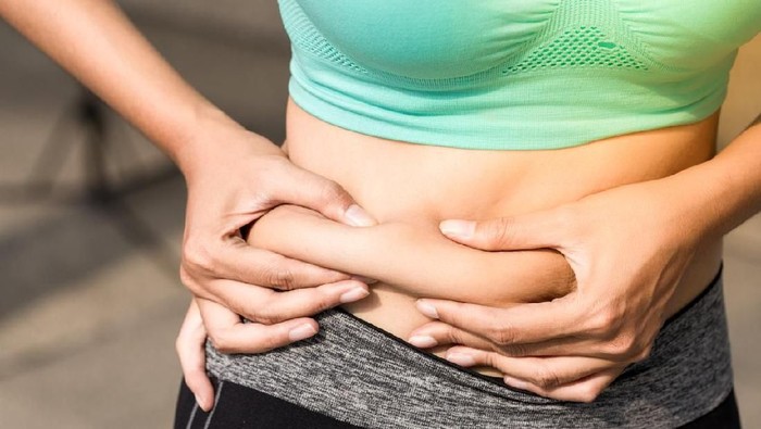 Overweight woman with tape is measuring fat on belly - obesity concept