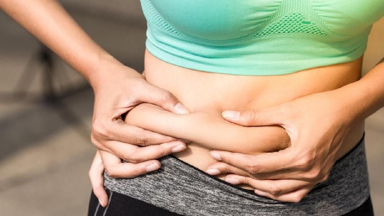 Overweight woman with tape is measuring fat on belly - obesity concept