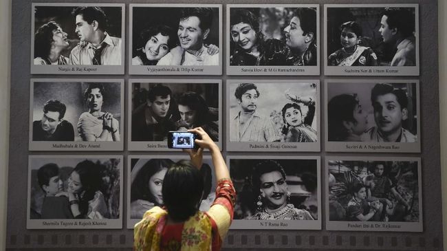 In this picture taken on January 22, 2019, a visitor takes a picture of a display with images of former Indian movie actors at the National Museum of Indian Cinema (NMIC), the country's first museum showcasing the history of its film industry, in Mumbai. - From silent black-and-white films to colourful blockbusters bursting with song and dance, a new museum tracing the evolution of Indian cinema has opened in the home of Bollywood. Costing 1.4 billion rupees (19.6 million USD), India's first national film museum is spread across a stylish 19th-century bungalow and a modern five-storey glass structure in south Mumbai. (Photo by PUNIT PARANJPE / AFP) / TO GO WITH AFP STORY INDIA-ENTERTAINMENT-FILM-BOLLYWOOD-HISTORY-MUSEUM,FOCUS BY UDITA JHUNJHUNWALA AND PETER HUTCHISON