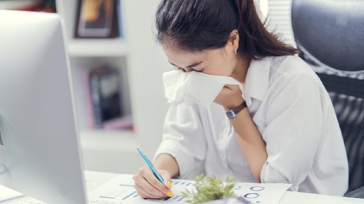 The businessman is unable to work, she is sick and sneezing heavily in bed.