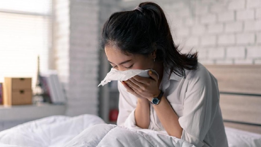 The businessman is unable to work, she is sick and sneezing heavily in bed.