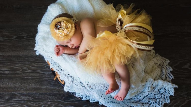 nama bayi Adorable beautiful newborn baby girl. One week old newborn baby sleeping in basket. Child in a yellow skirt