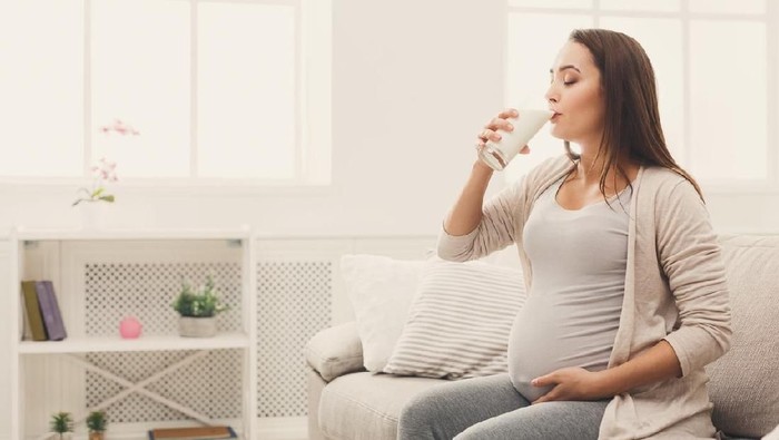 Pregnant woman drinking glass of milk copy space. Young expectant lady enjoying healthy drink. Healthcare, nutrition, vitamins, pregnancy concept