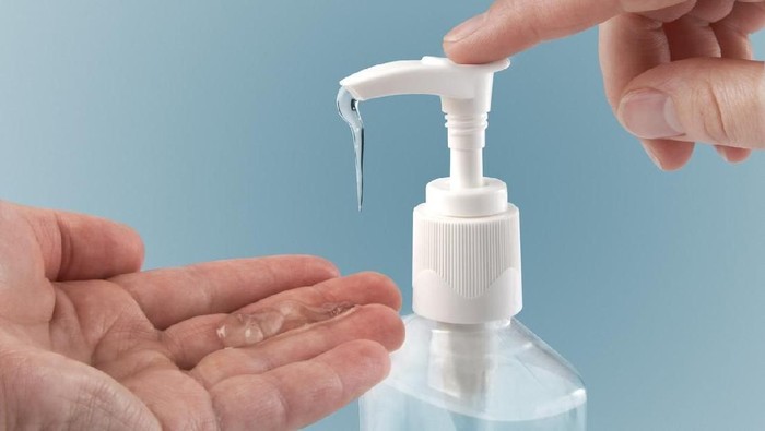 Pumping hand sanitizer into hand.