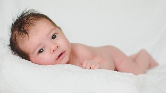 baby boy lying in bed, in blue cap