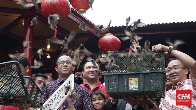 Anies mengajak dua anaknya berkeliling area kompleks wihara lalu melepas burung pipit yang merupakan tradisi khas perayaan Imlek.