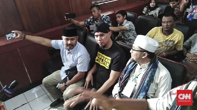 Ahmad Dhani mengenakan kaus hitam bertuliskan "tahanan politik" tanpa rompi tahanan saat tiba di Pengadilan Negeri Surabaya untuk menjalani sidang perdana.