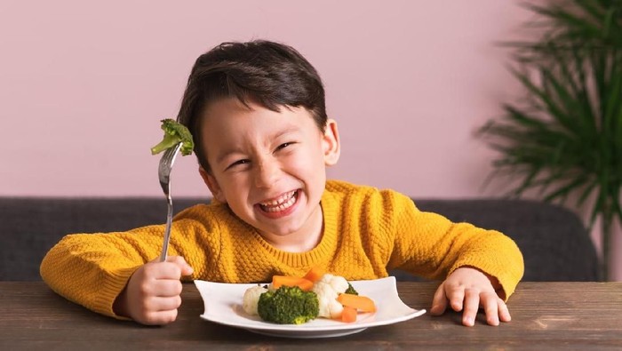 Little boy is enjoying his stir fry dinner and socialising with his family at home.