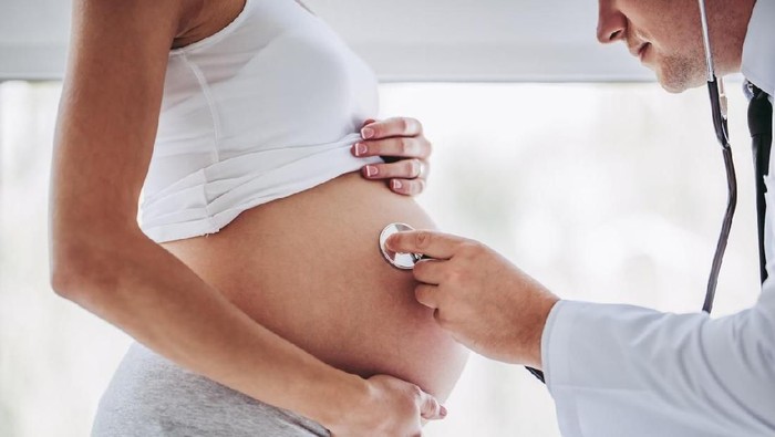 Young couple at the doctor. Holding hands and looking on each other while doctor is showing the ultrasond picture of their future baby.
