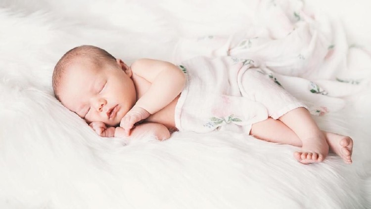 Sleeping newborn baby in a wrap on white blanket. Beautiful portrait of little child girl 7 days, one week old.