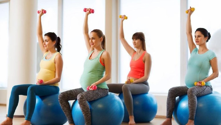 904136250 Beautiful pregnant woman workout. Doing fitness on last months of pregnancy. Yoga. Standing on white brick background with sports mat.