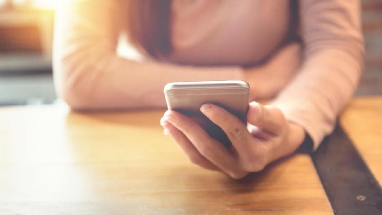 Closeup of thoughtful young Asian woman holding mobile phone and surfing Internet. Attractive student taking selfie at cafe. Communication and work balance concept