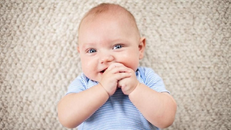 184351899 Color image of a baby boy lying on his back on carpet inside a home.