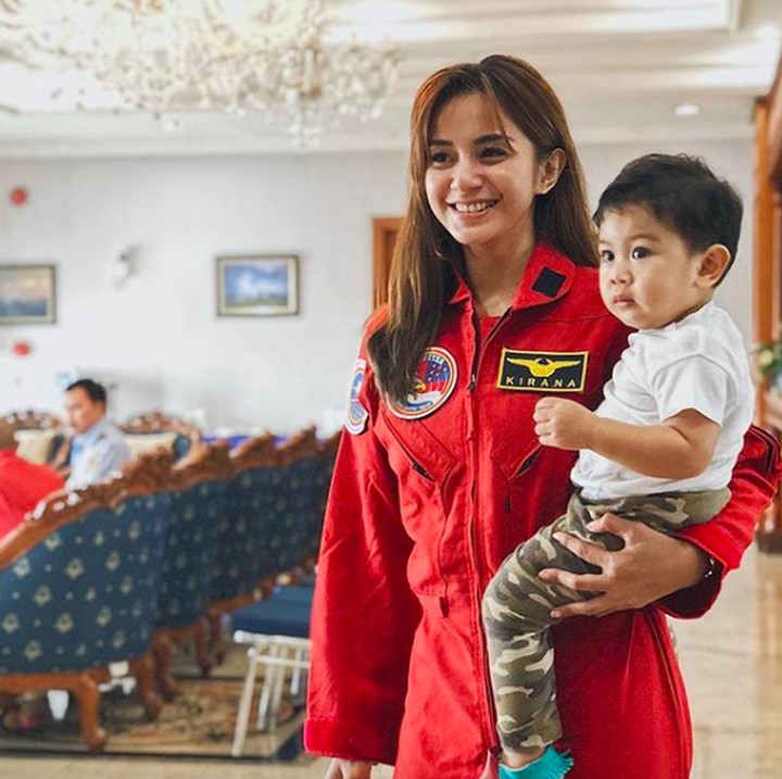 <p>Tak ingin melewatkan waktu bersama Kyo, wanita 31 tahun itu sering membawanya saat bekerja. Termasuk saat berkesempatan datang ke Pangkalan TNI AU Halim Perdanakusuma. Mama Kirana memakai seragam pilot jupiter berwarna merah sambil menggendong Kyo. (Foto: Instagram/ @kiranalarasati)</p>