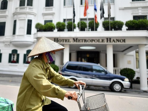 A Vietnamese woman rides her bicycle past the Metropole Hotel in Hanoi on February 21, 2019 ahead of the second summit between US President Donald Trump and North Korean leader Kim Jong Un. (Photo by Manan VATSYAYANA / AFP)