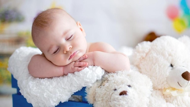 Little baby boy with knitted hat, sleeping with cute teddy bear toy at home