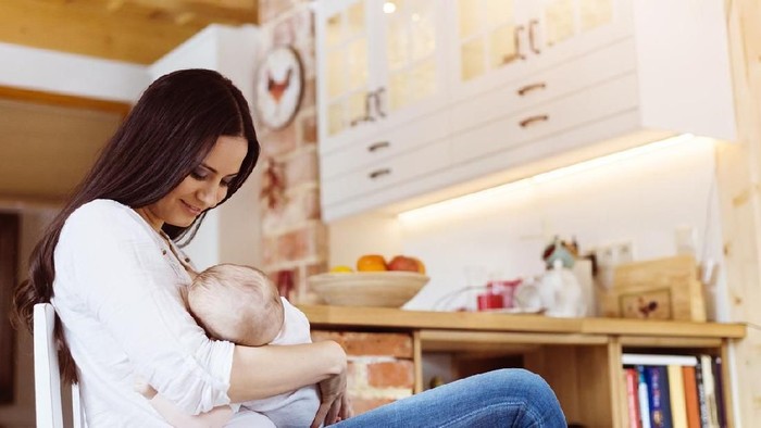 Mother breastfeeding her little baby girl in her arms.