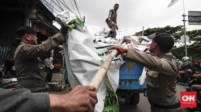 Petugas Satpol PP menertibkan alat peraga kampanye (APK) yang tidak sesuai aturan di jalan protokol kawasan Setiabudi, Jakarta, Rabu, 13 Maret 2019. Penertiban APK serentak dilakukan di wilayah Jakarta mulai hari ini.CNNIndonesia/Safir Makki