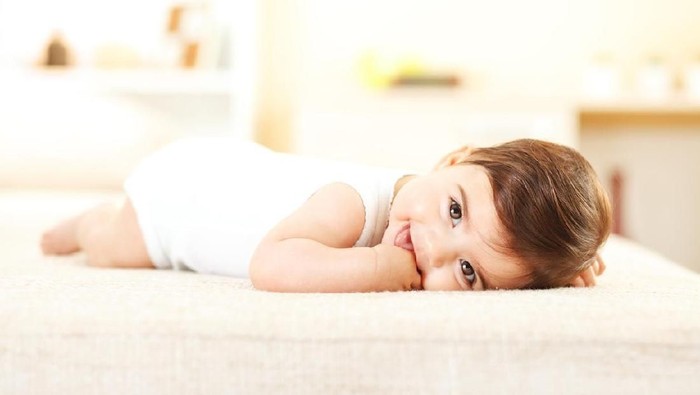 Little baby girl lying on bed,smiling and looking at camera.