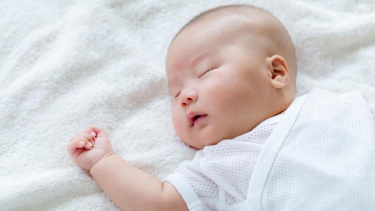 Close-up of a newborn sleeping at blue bed background. ( Baby born 11 days )